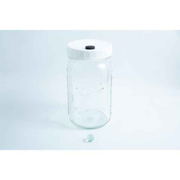 A Mycology Ball Kilner jar with injection port and air vent, 1L genuine and autoclavable, sits next to a small glass marble on a white background.