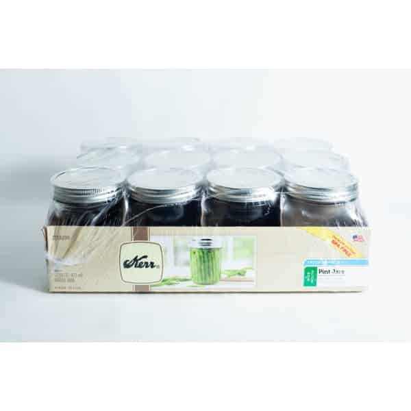 A sealed pack of twelve Kerr wide mouth Mason jar glass pint size 473ml with lids and bands, packed in a cardboard tray with plastic wrapping.