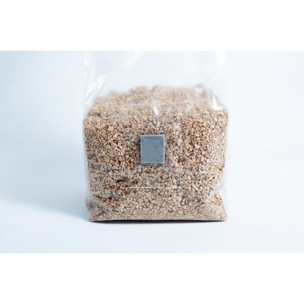 A clear plastic bag of Organic Brown Rice Flour BRF 4X 500g for PF Tek, sealed and upright on a white surface, filled with small brown granules.