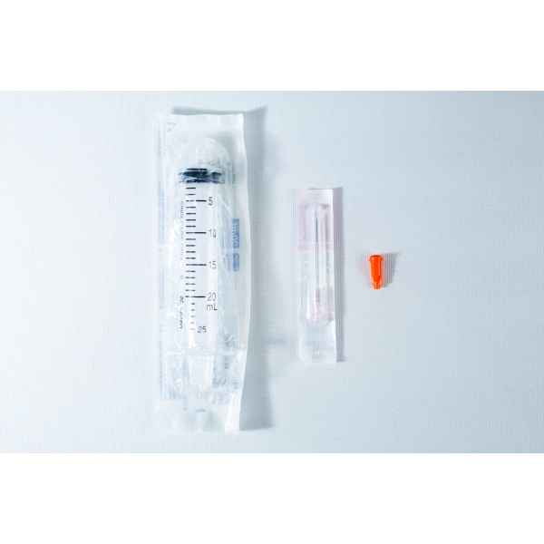 A packaged syringe, a packaged needle, and an orange needle cap on a white surface.