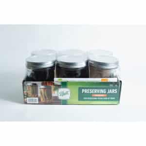 A set of six Ball Mason pint jars with wide mouths are organised in a cardboard box labelled "Preserving Jars" and shown against a white background.