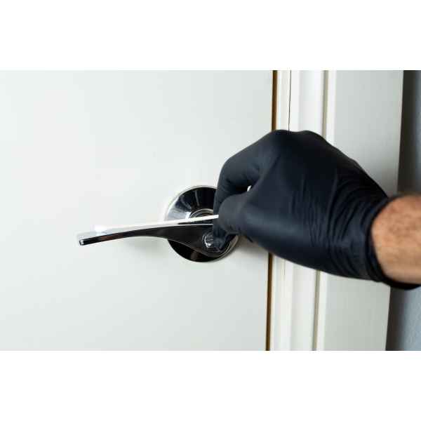 A gloved hand holds a cotton bud near a door handle, likely collecting evidence for a school experiment using the Agar Petri dish MEA School Science Fun Project Kit.