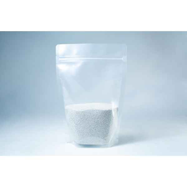 A clear resealable pouch containing white coarse Natural Gypsum mushroom supplement grain and substrate stands on a light background—perfect for storage and use.