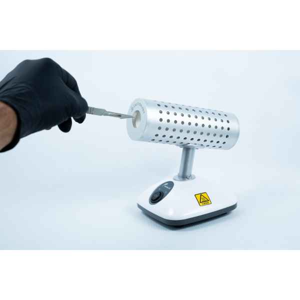 A gloved hand inserts a tool into the Infrared Steriliser Bacti Cinerator Lab tool, which features a warning sign on its base, in the laboratory.