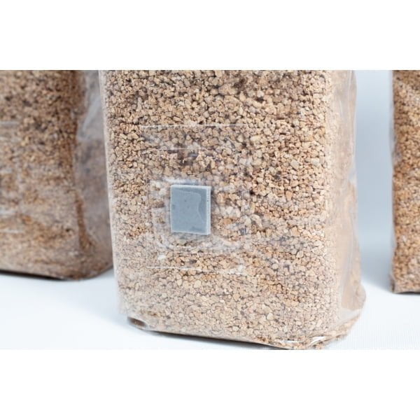 A clear bag of brown grains with a grey patch, ideal for mushroom substrates—perfect for PF Tek using 3×1kg Organic Brown Rice Flour (BRF) & Vermiculite bags.