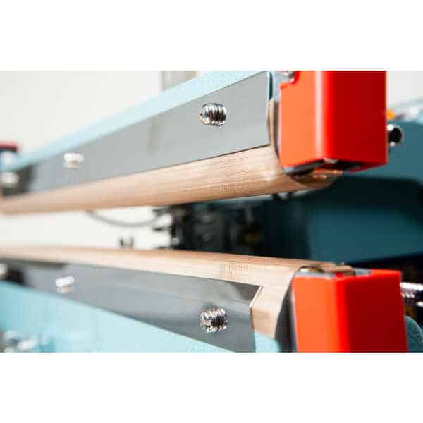Close-up view of industrial machine parts with metal bars and red components, featuring the Heat Sealer 450mm with 10mm Seal | Benchtop Model for efficient sealing operations.