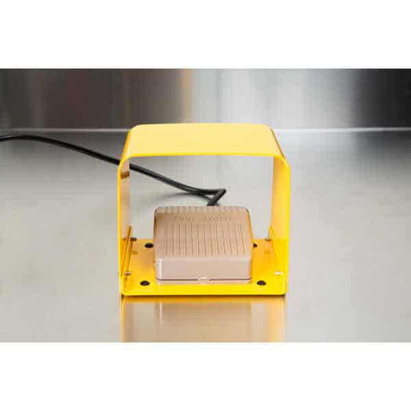 A beige footswitch under a yellow cover rests on a stainless steel surface, ready to operate the Heat Sealer 450mm with 10mm Seal | Benchtop Model.