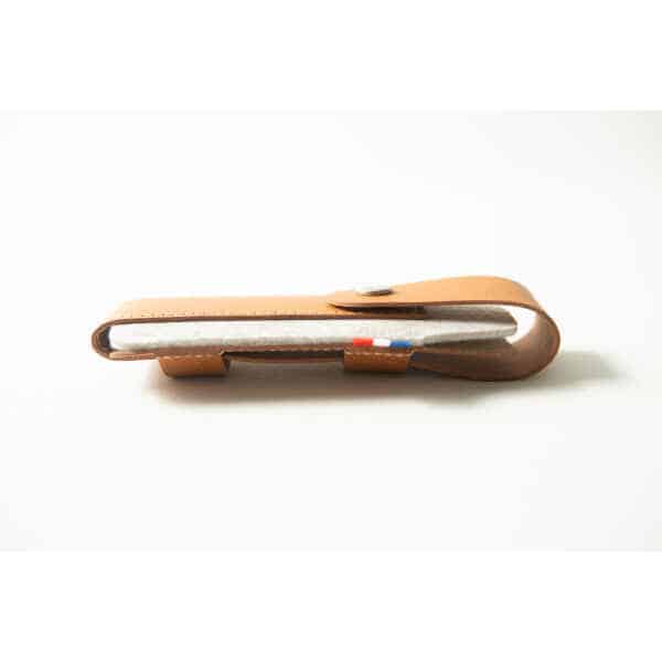 A brown leather Opinel Sheath with a buttoned flap, holding a white fabric item featuring a small coloured tag.