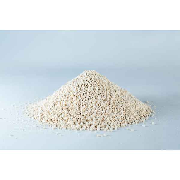 A small mound of Natural Gypsum coarse grade mushroom supplement grain and substrate, featuring beige, granular powder, rests on a light grey surface.
