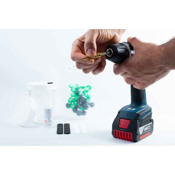 Hands insert the Drill Bit for hole sizes 3mm-12mm Titanium Coated into a cordless drill; various small items are placed on a white surface in the background.