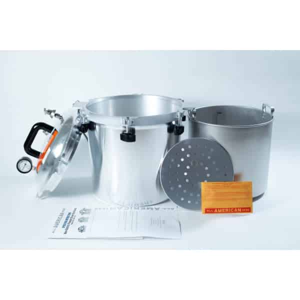 A silver pressure cooker with lid, inner pot, rack, instruction manual, and orange card displayed on a white surface.