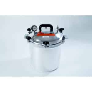 A stainless steel pressure cooker with a gauge, handle, and safety valves on a white background.