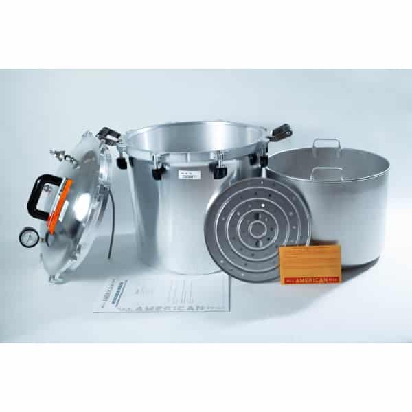 All American pressure cooker with lid, inner pot, metal rack, instruction manual, and orange card displayed.