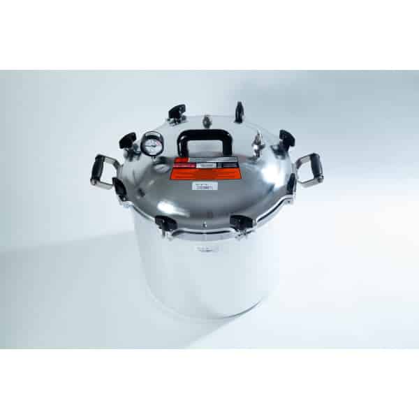 A large stainless steel pressure cooker with a black handle and pressure gauge on a white background.