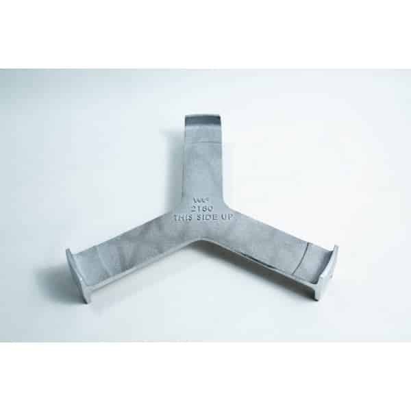 Grey metal object with three prongs and “THIS SIDE UP” engraved at the centre, placed on a white surface.