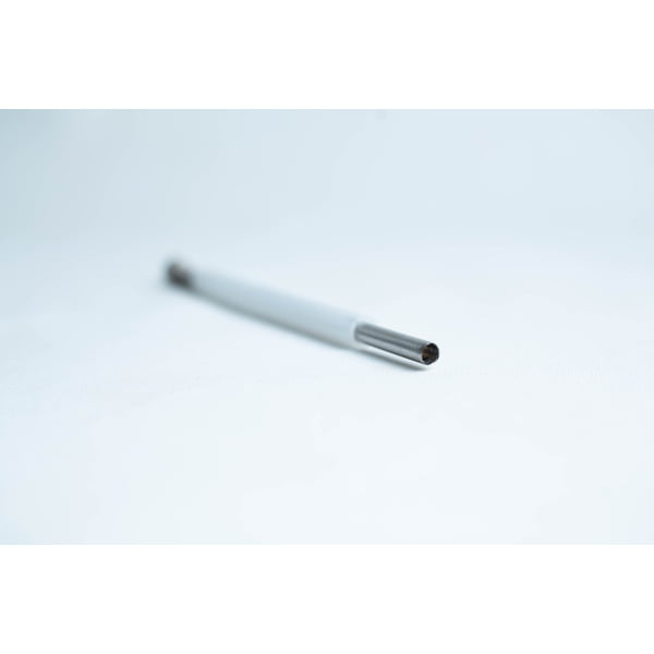 A close-up of a pen refill lying on a white surface with a blurred background.