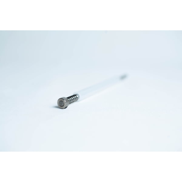 A metal spring pen refill lying on a white surface, photographed with a shallow depth of field.