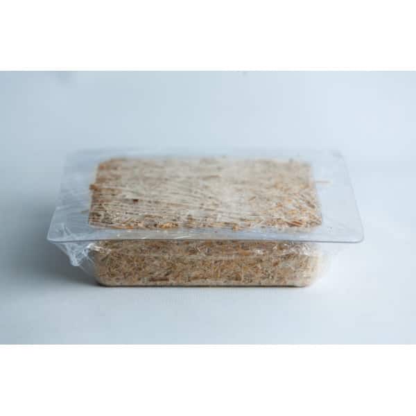 A rectangular block of food wrapped in plastic on a white surface.
