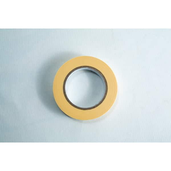 A roll of yellow masking tape on a light blue surface, viewed from above.