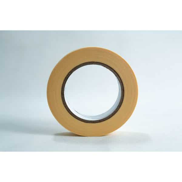 A roll of beige masking tape stands upright on a white surface against a light background.