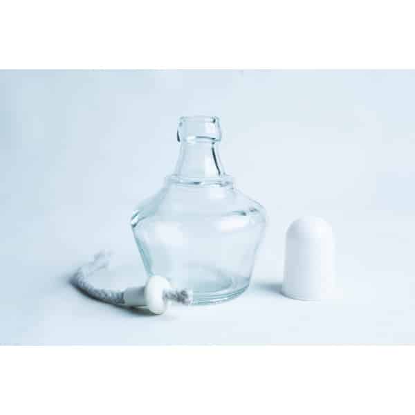 A small empty glass bottle with its white cap and a wick placed beside it on a white background.