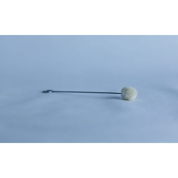 A single metal stick with a cotton bud lies on a smooth, light blue surface.