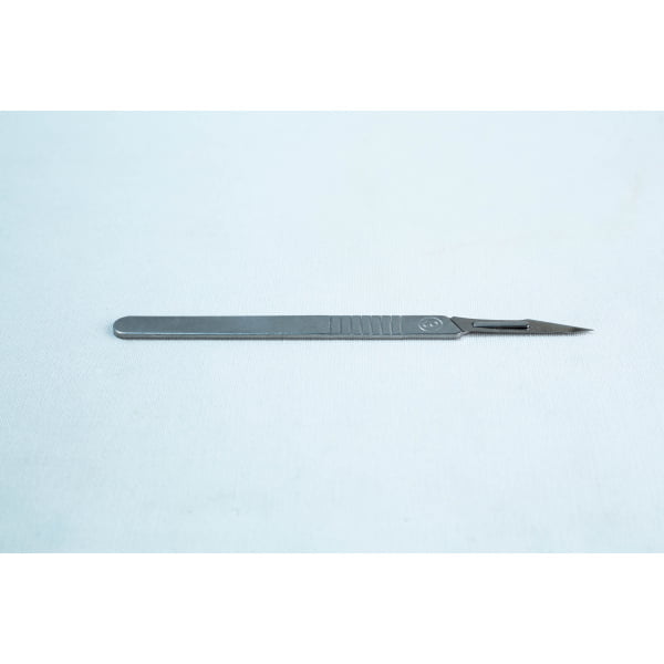 A metal surgical scalpel lies on a plain light surface with its blade facing right.