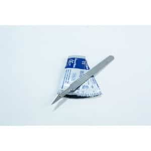 A metal scalpel rests on top of a blue and white sterile packaging on a white surface.