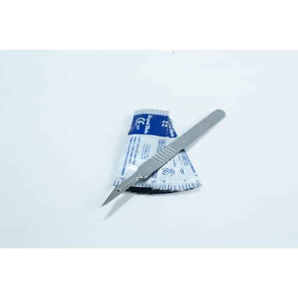 A metal scalpel rests on top of a blue and white sterile packaging on a white surface.