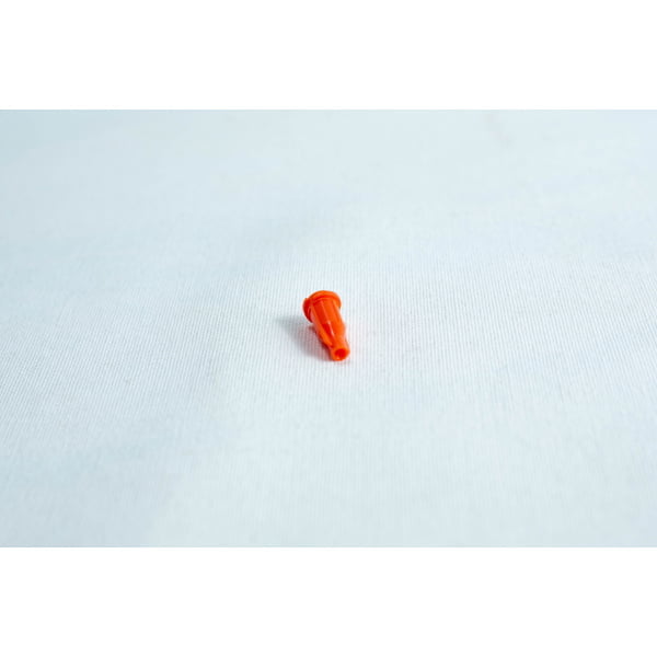 Small orange plastic object on a plain white surface.