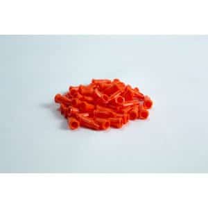 A pile of small, orange plastic caps on a white surface.