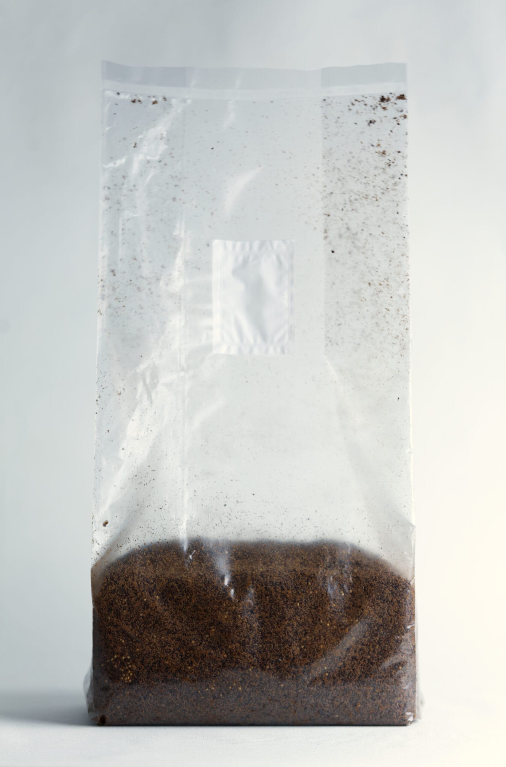 Mycelium Growth Medium | Hemp Substrate or Sawdust Substrate 3 Clear plastic bag filled with brown coffee grounds against a plain background.
