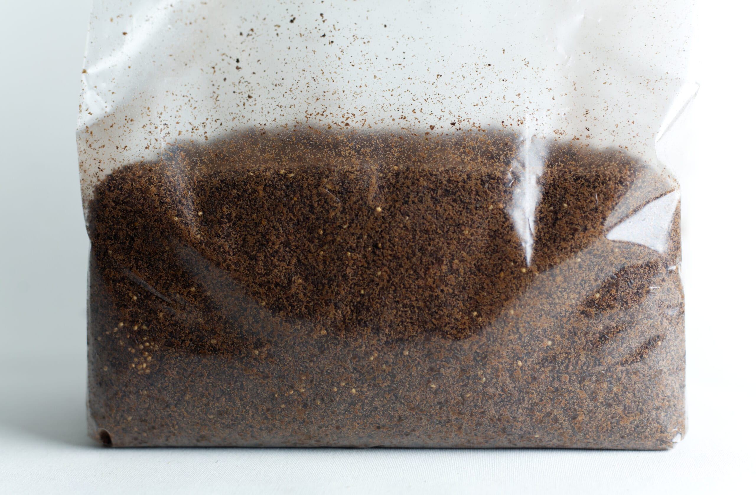 Mycelium Growth Medium | Hemp Substrate or Sawdust Substrate 1 Clear plastic bag filled with brown ground coffee against a white background.