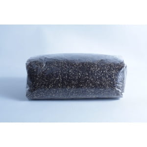 A block of dark soil or compost, perfect for the Monotub Mushroom Growing Kit-Premium, is wrapped in clear plastic and set against a plain light background.