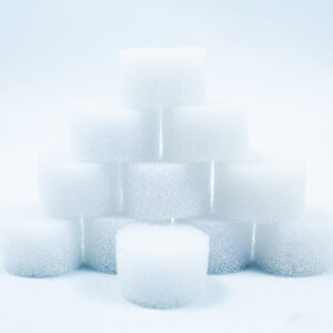 A pyramid of white, round foam sponges stacked on a white surface with a soft, light background.