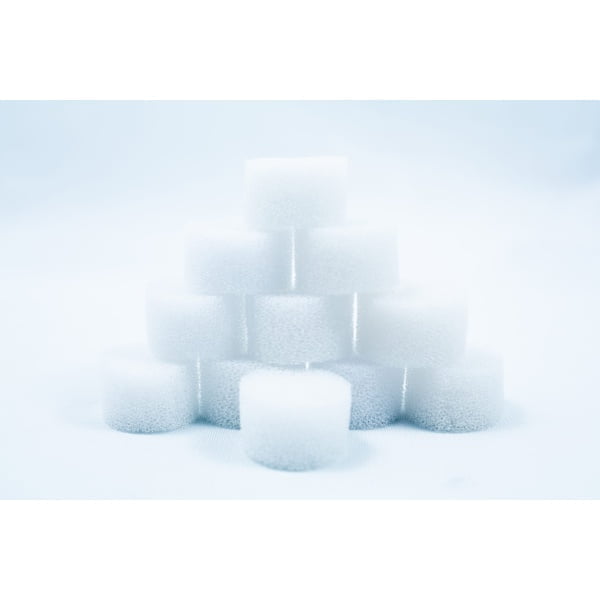 A pyramid of white, round foam sponges stacked on a white surface with a soft, light background.