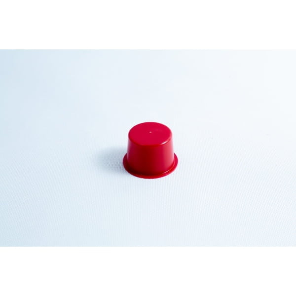 A small red plastic cup turned upside down on a plain white surface.