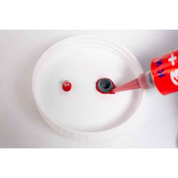 High Temperature RTV Silicone-Red is being applied around a grey nozzle on a white plastic surface.