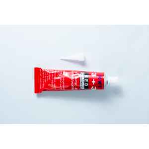 A red tube of High Temperature RTV Silicone-Red with a white cap placed above it on a white background.