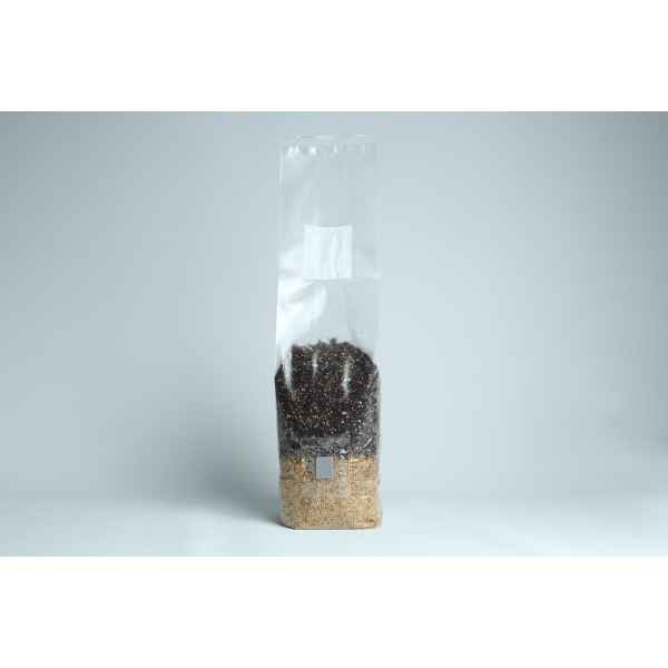 Clear plastic bag filled halfway with mixed grains and seeds, standing upright on a plain background.