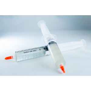 Two single-use syringes with orange caps containing Mushroom Liquid Culture | Wood Ear | Auricularia auricula-judae lie on a white surface, one filled with a clear liquid.