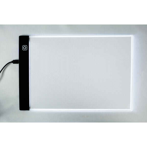 A rectangular LED light pad with a black edge and glowing white surface, plugged in on the left-hand side.