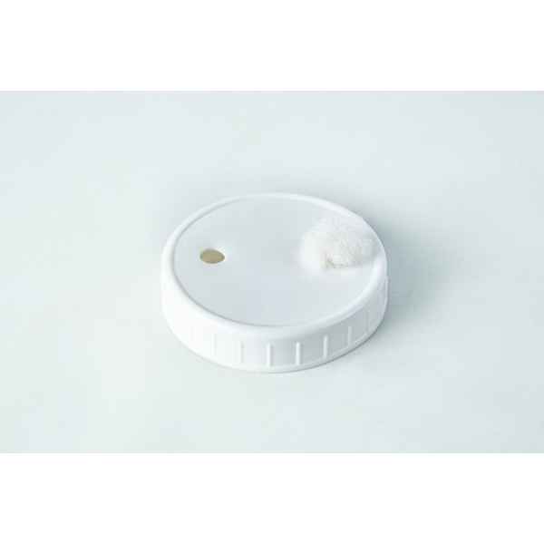 A white plastic cap with a small round object.