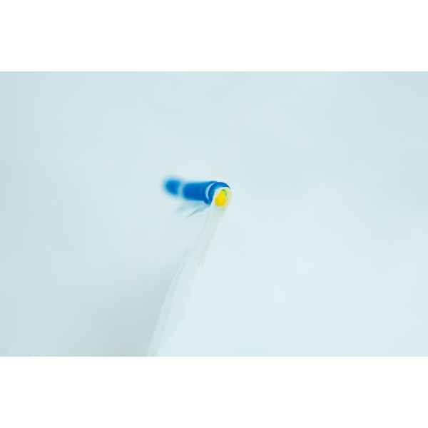 Close-up of a blue and yellow biro tip on a white background, with a shallow depth of field.