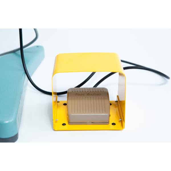 The Vertical Foot Heat Sealer VHVD 450mm Double 10mm by Venus features a yellow-covered foot switch with cable, positioned on a white surface beside green equipment.