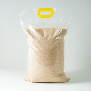 A clear plastic bag containing Certified Organic Biodynamic Rye berry grain, light brown granules, sealed with a yellow handle at the top.