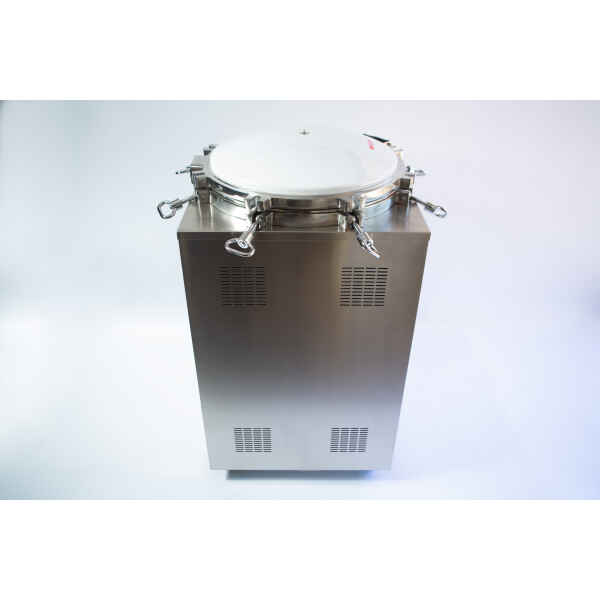 A stainless steel autoclave machine with a round, sealed lid and catches on a plain background.
