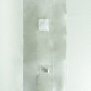 A translucent plastic sheet with two small square patches is displayed on a light, plain background.