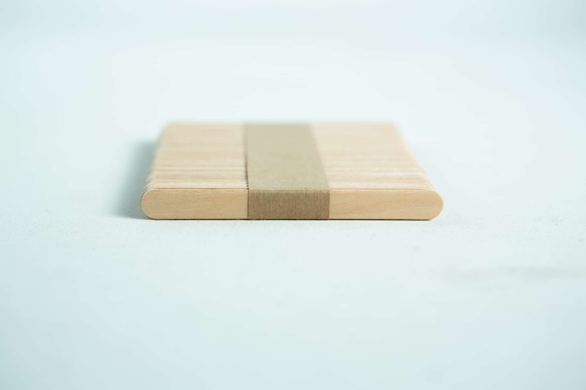 Birch hardwood sticks for slants 2 A stack of ice lolly sticks, neatly bundled with a brown paper band, is arranged on a white surface.