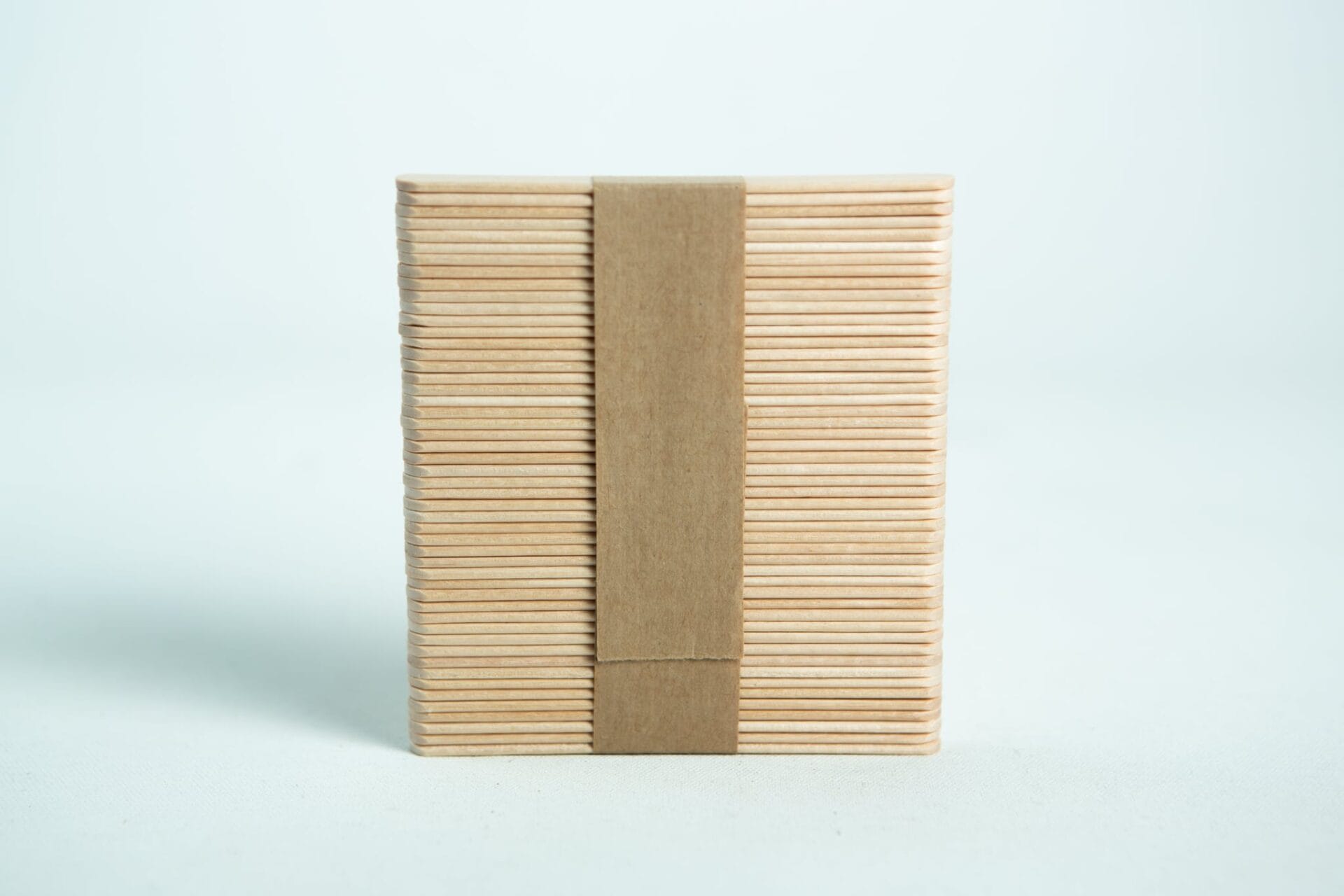 Birch hardwood sticks for slants 1 A bundle of ice lolly sticks, neatly wrapped with a brown paper band, is set against a white background.